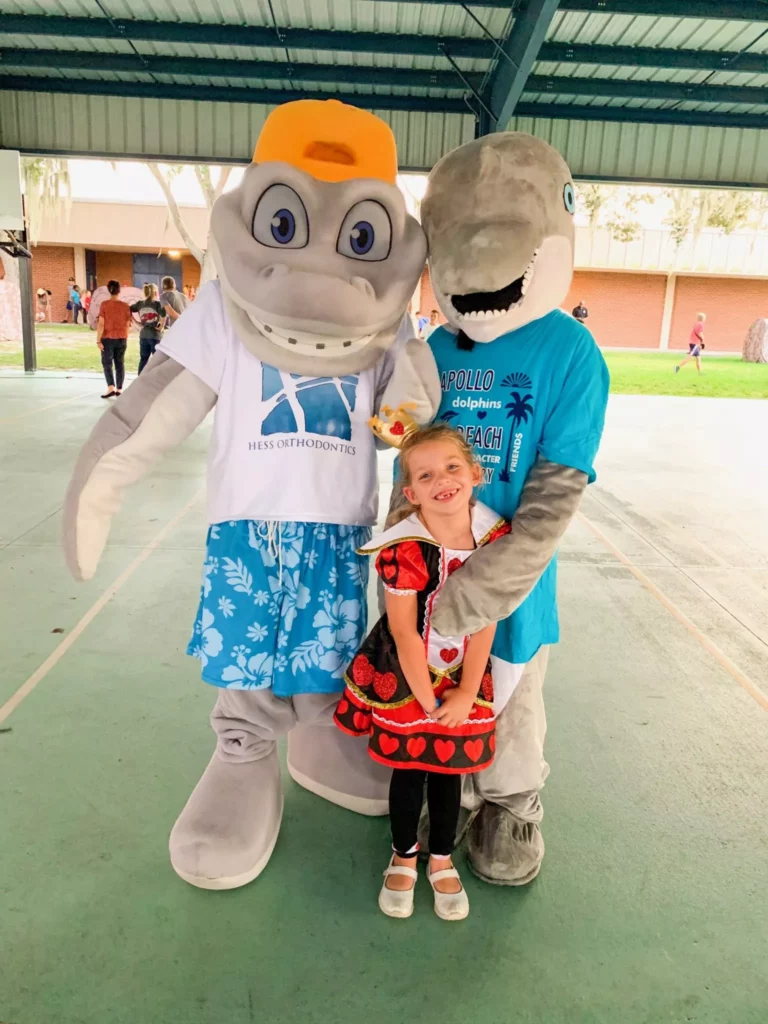 two shark mascots with a young girl