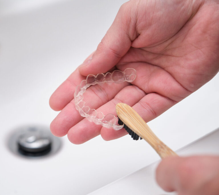 Washing and removing organic residues with a bamboo toothbrush from orthodontic invisible braces.