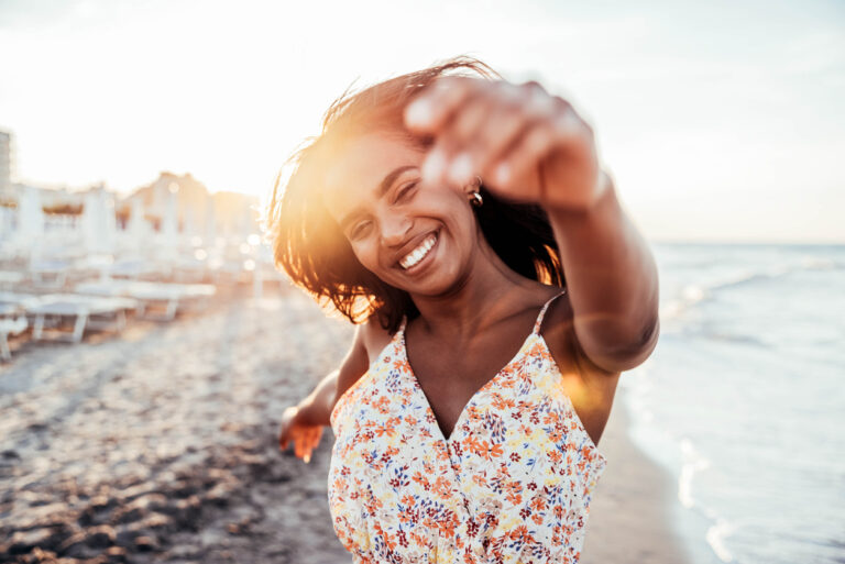 Cheerful woman smiling at the beach on sunset